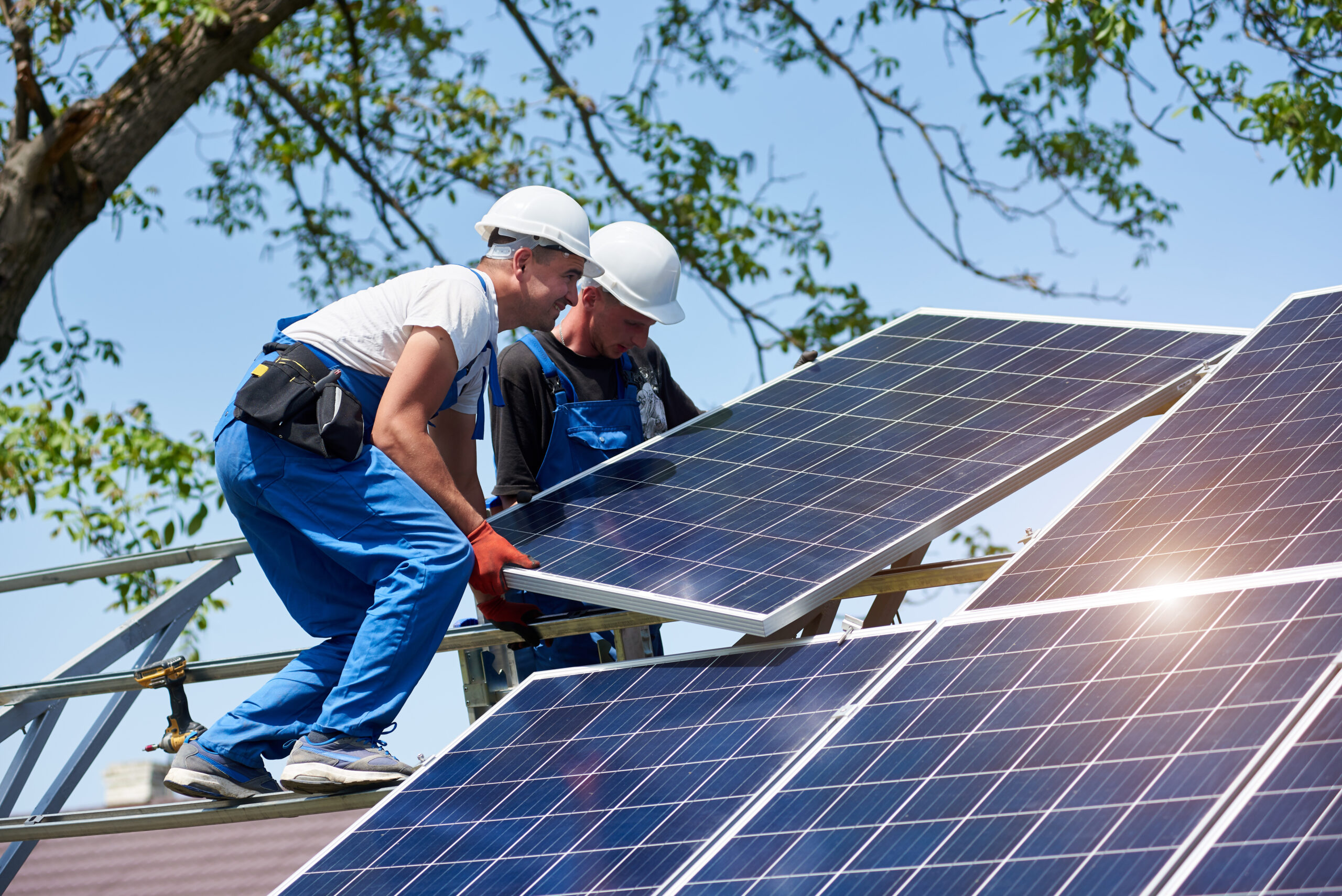 Two solar installers move a panel into place
