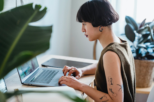 A woman sits at a desk, working on a laptop.